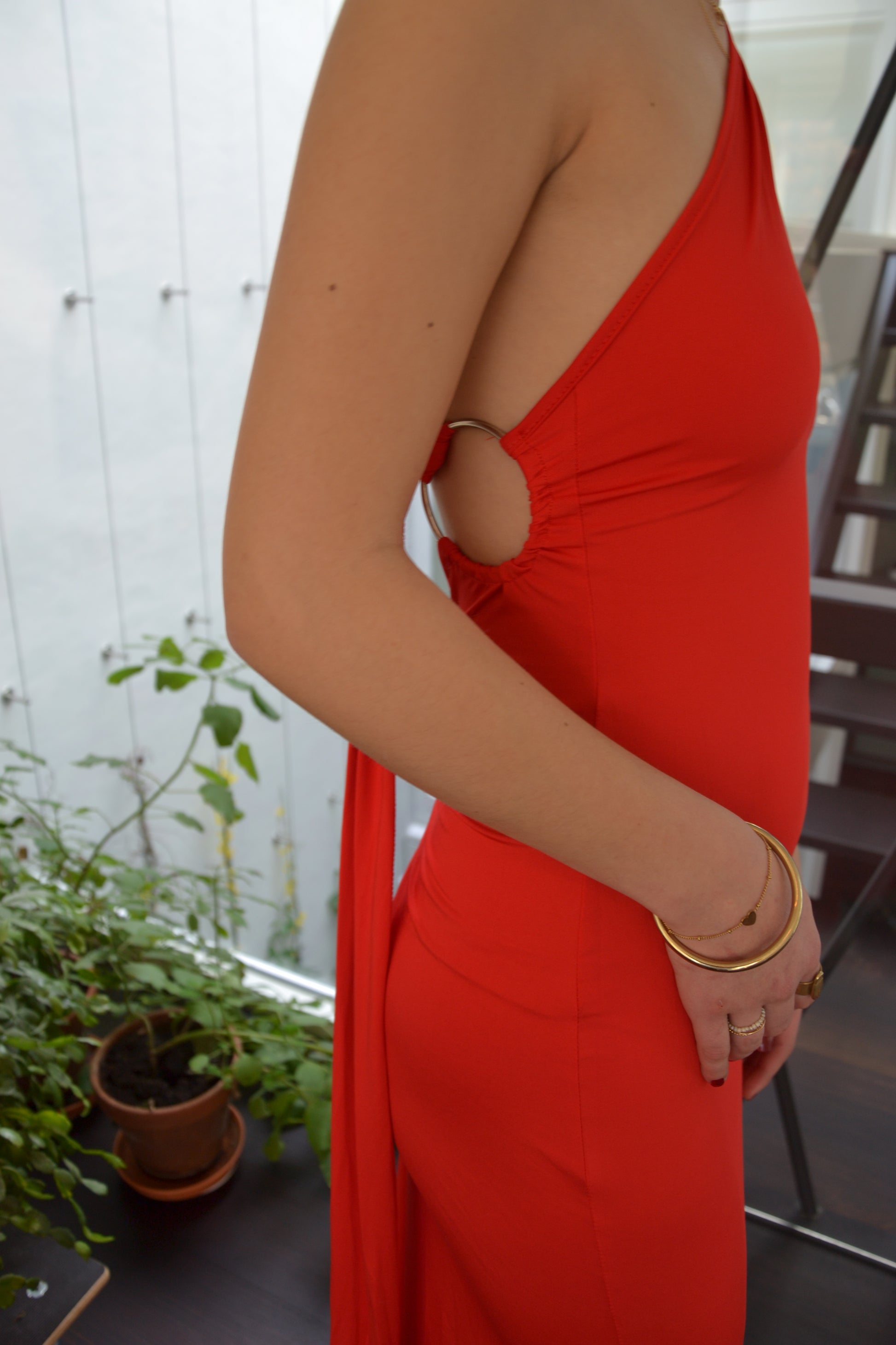 Close-up van het bovenstuk van de Red Ring Dress met asymmetrische halslijn, avondjurk huren bij Pineloue.